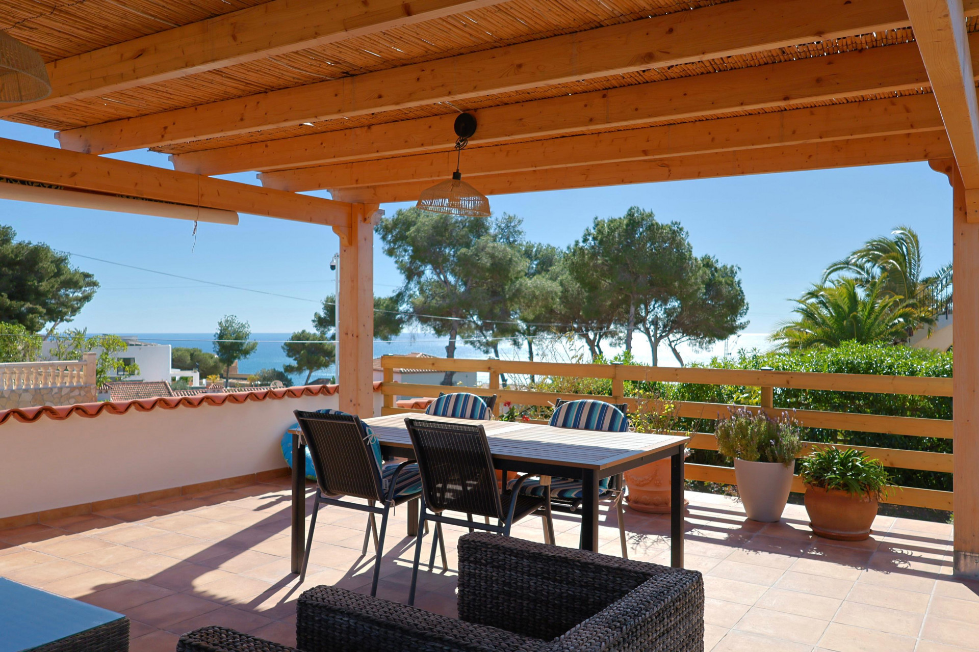 Überdachte Terrasse mit Meerblick und Essmöbeln.