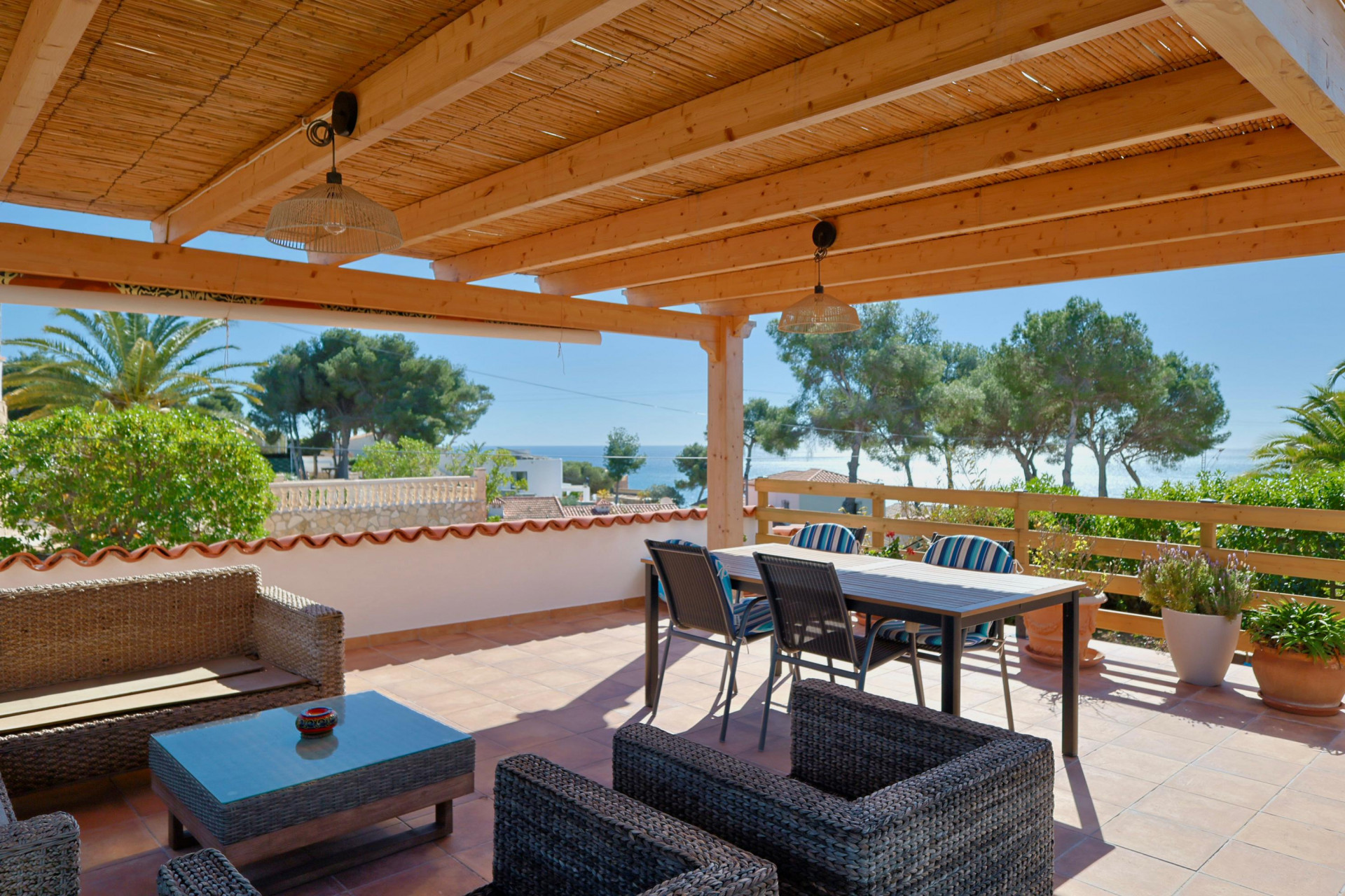 Überdachte Terrasse mit Meerblick und Rattanmöbeln.