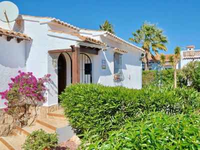Fassade einer mediterranen Villa mit Bougainvillea und Holzbogeneingang.