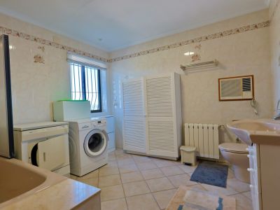 Funktionales Badezimmer mit Waschmaschine, Trockner und geräumigem, weißem Lamellenschrank.