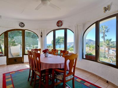 Helles Esszimmer mit Meerblick, umgeben von Bogenfenstern und rustikalem Dekor.