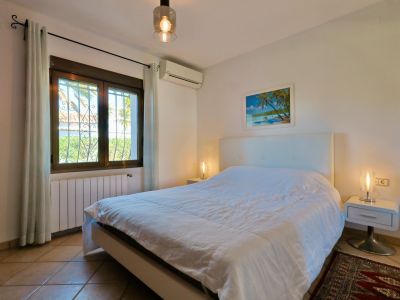 Helles Schlafzimmer mit Doppelbett, modernen Nachttischen und Fenster mit Blick nach draußen.