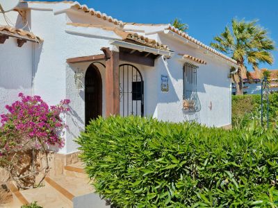 Mediterrane Villenfassade mit Bougainvillea und Holzdetails.