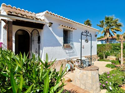 Mediterrane Villenfassade mit dekorativem Brunnen und üppigem Garten.