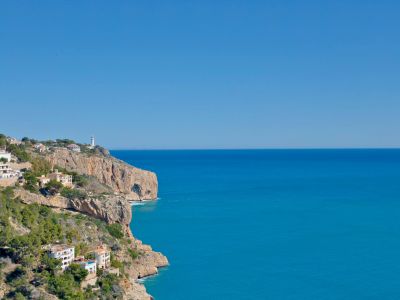 Panoramablick auf die felsige Küstenlinie und das Mittelmeer von Jávea aus, mit weißen Häusern am Hang.