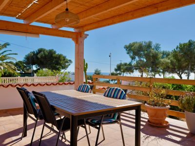 Überdachte Terrasse mit Esstisch und Blick auf das Mittelmeer.