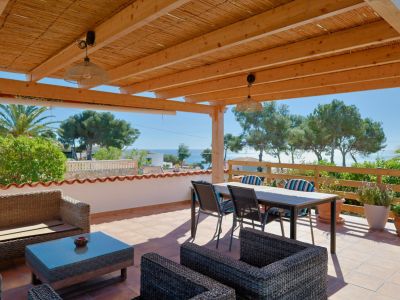 Überdachte Terrasse mit Meerblick und Rattanmöbeln.