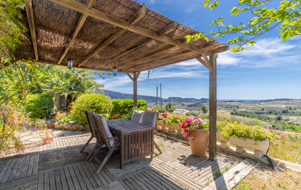 Außenterrasse mit Holzpergola und Heidekrautbedeckung, Essbereich aus Teakholz und Panoramablick über die Weinberge bis hin zum Mittelmeer.