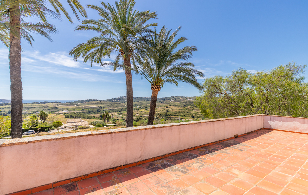 Hochgelegene Terrasse mit traditionellen Terrakottafliesen und Panoramablick über terrassierte Weinberge bis hin zum Mittelmeer am Horizont.