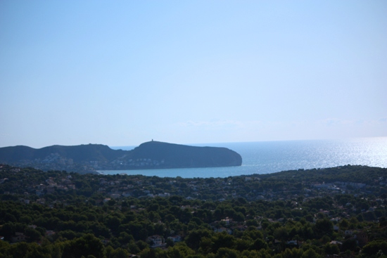 Panoramablick vom Anwesen auf das Mittelmeer und die Landzunge von Moraira, eingebettet in eine grüne Landschaft aus Pinien und Wohngebieten.