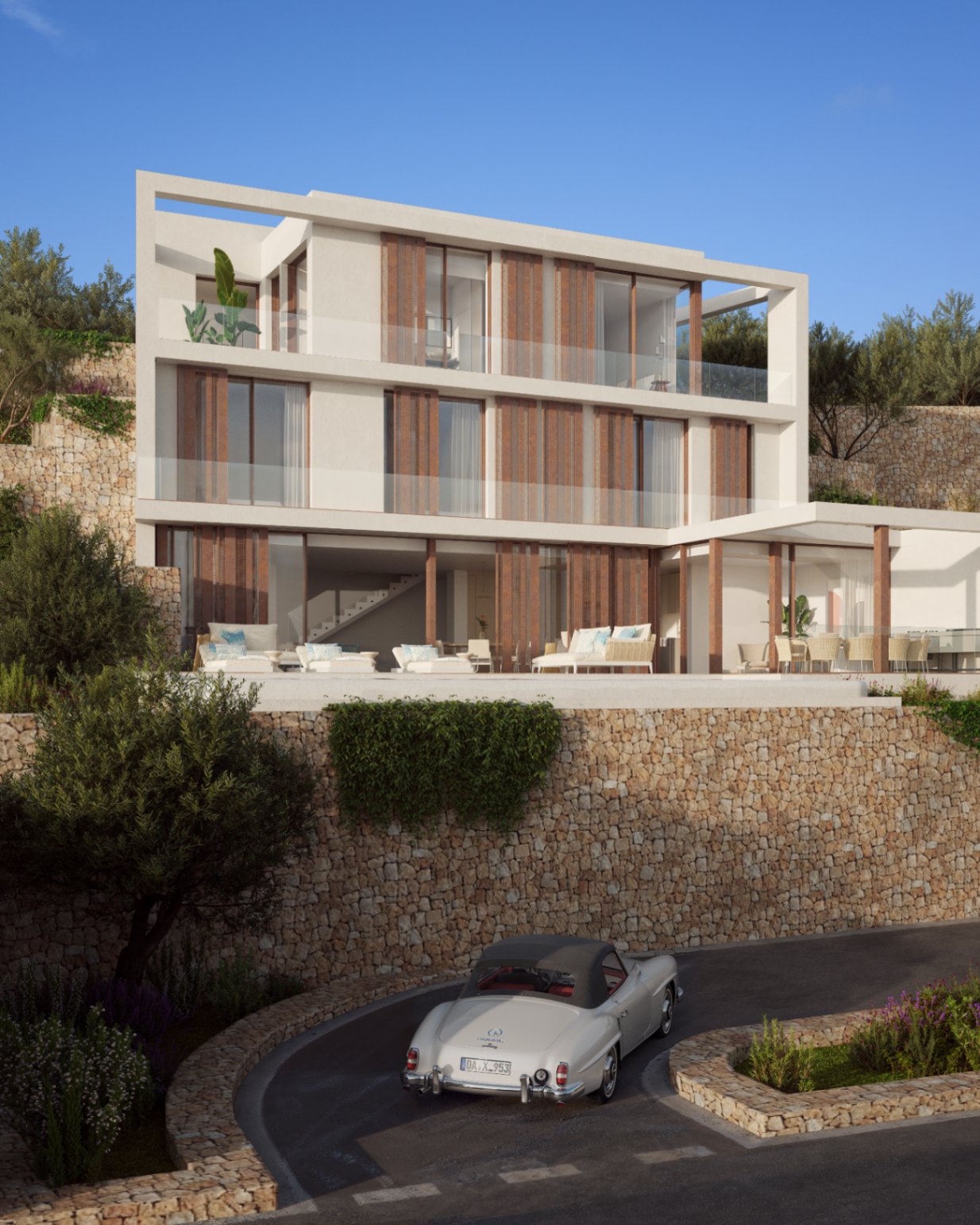 Dreistöckige Fassade mit Natursteinmauern, Holzlamellen und großzügigen Glasbalkonen. Der Außenbereich umfasst eine Lounge-Terrasse und mediterrane Bepflanzung auf Hanglage.