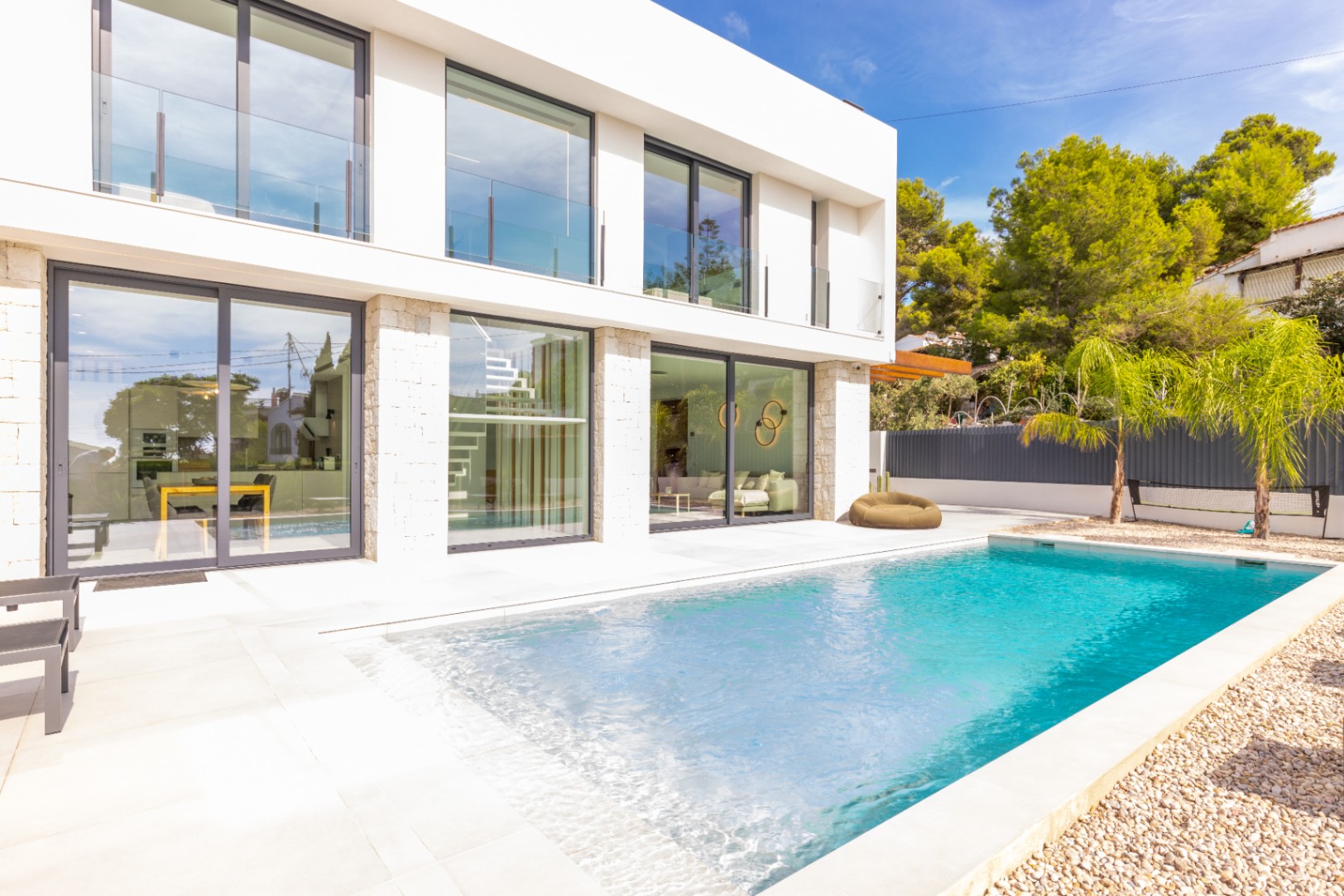 Blick auf den privaten Pool, die geflieste Terrasse und die moderne Fassade der Villa in Benissa.