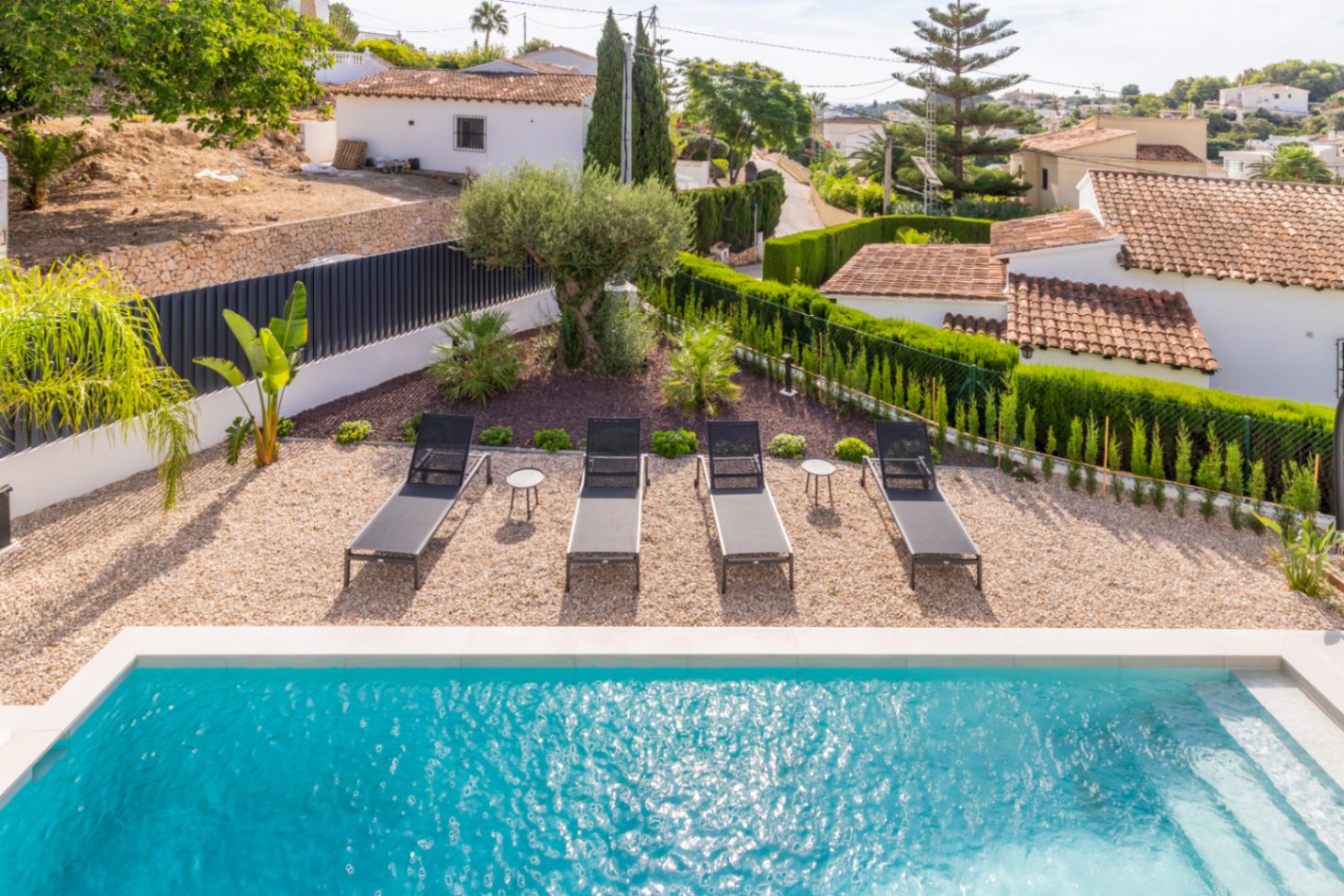Erhöhte Ansicht des Pools mit Sonnenliegen, Kies und Hecken Garten in Benissa.