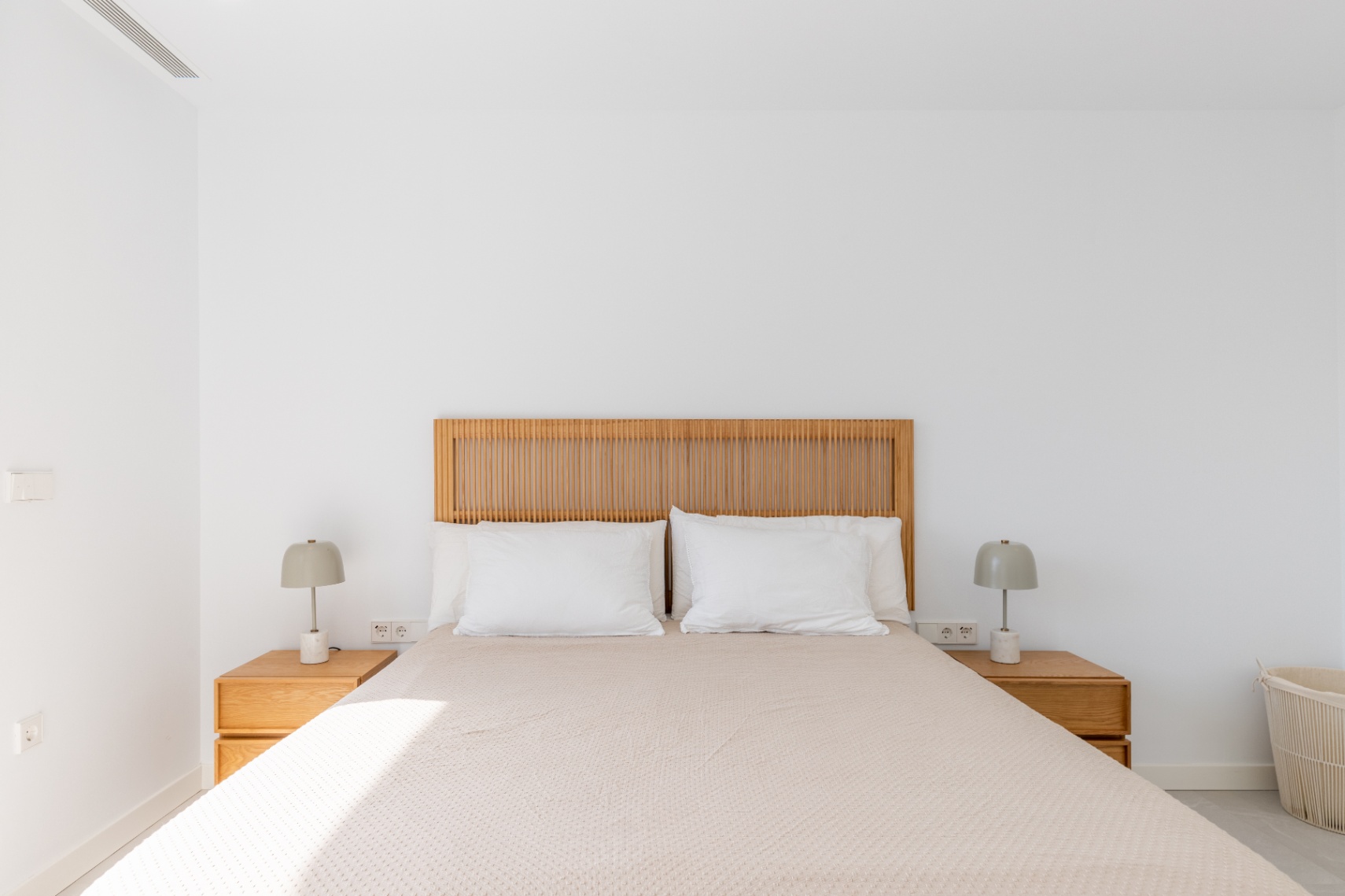 Helles Schlafzimmer mit Holzkopfteil und passenden Nachttischen.