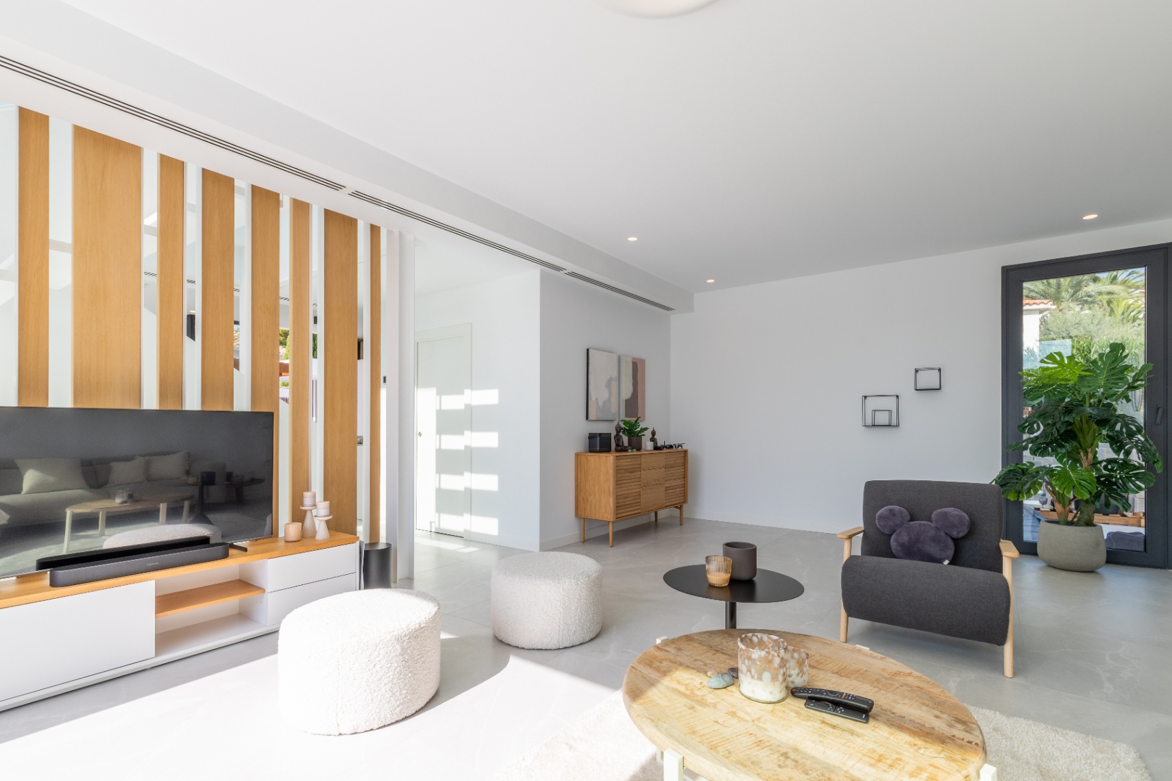 Helles Wohnzimmer mit Holztrennwand, modernen Möbeln und minimalistischen Designelementen.