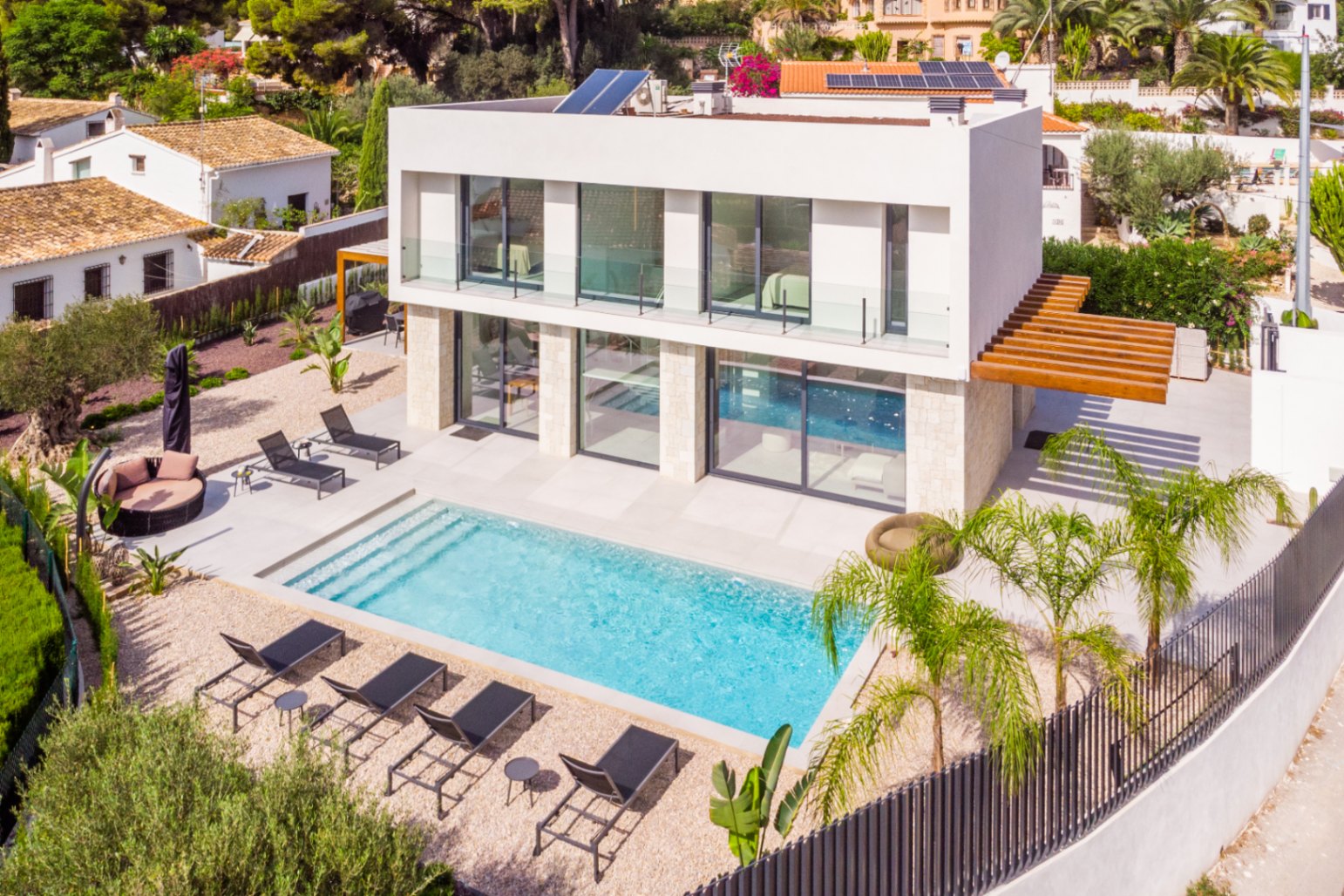 Luftaufnahme der Villa mit türkisfarbenem Pool, umgeben von Liegestühlen und hellem Kies.