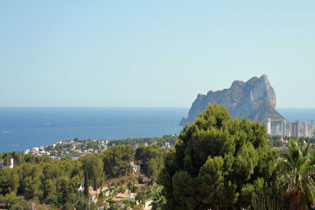 Panoramablick auf das Mittelmeer und den Peñón de Ifach von der erhöhten Lage der Villa, umgeben von einer dichten Vegetation aus Pinien.