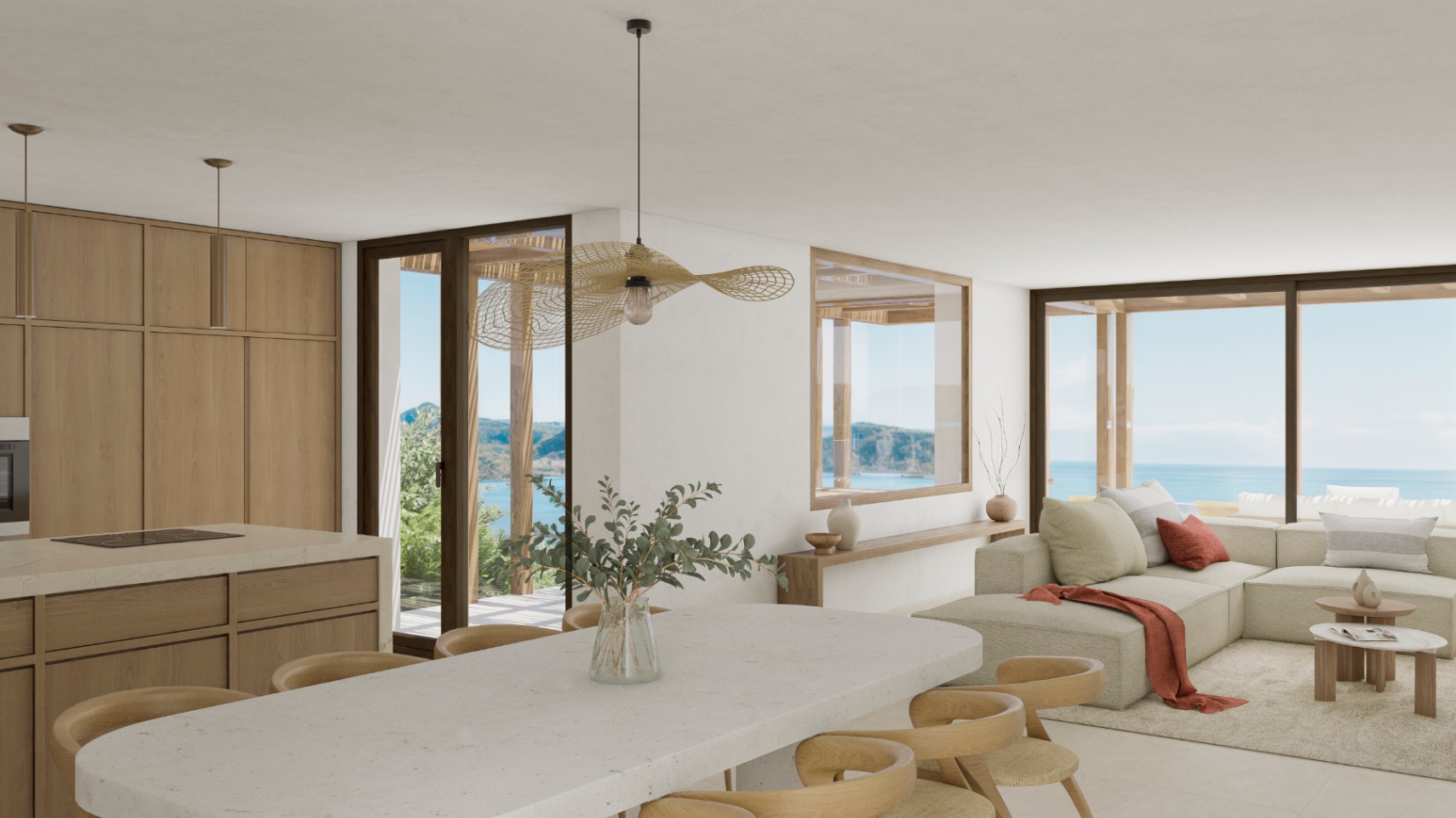 Helles Interieur mit offener Küche, Steininsel und Meerblick.