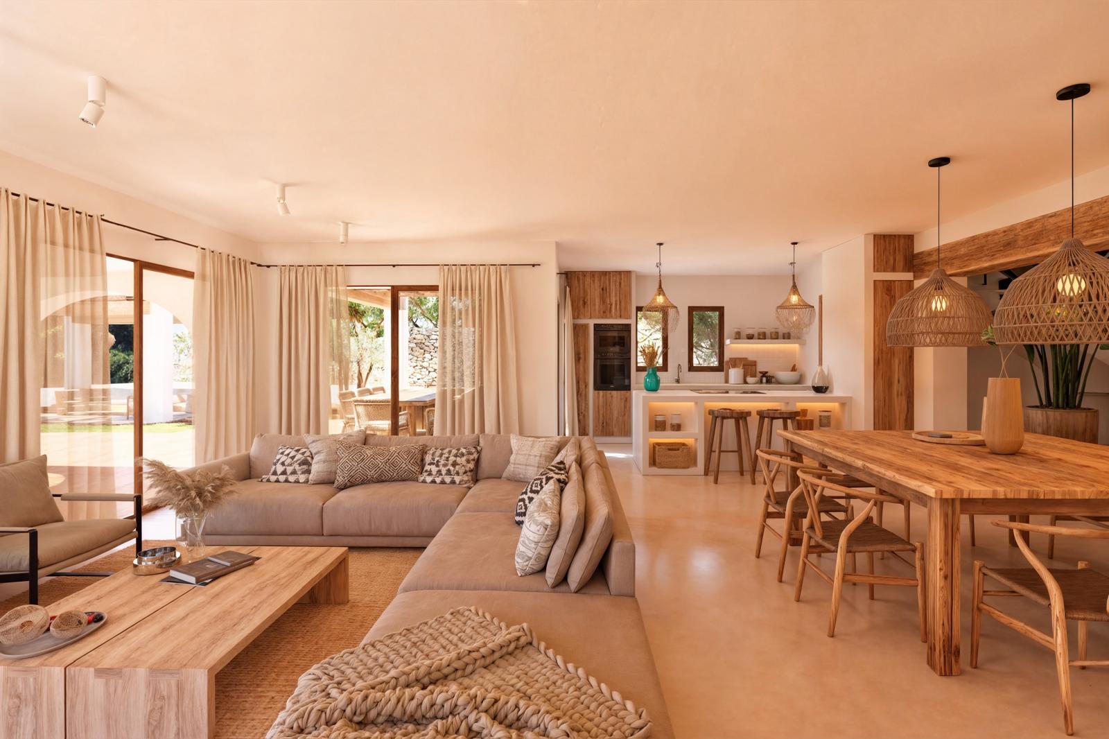 Offener Wohn- und Essbereich mit Naturholzmöbeln, neutralen Textilien und integrierter Küche. Große Glasfronten und Korbleuchten unterstreichen das elegante mediterrane Design.