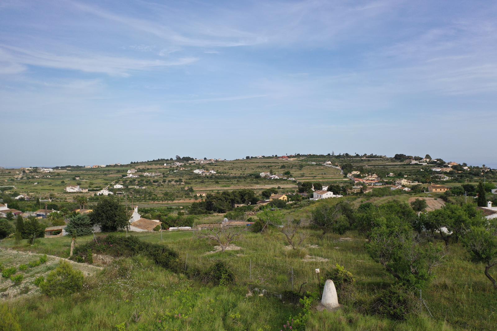 Panoramablick auf die natürliche Umgebung mit terrassierten Hügeln und mediterraner Vegetation unter klarem Himmel.