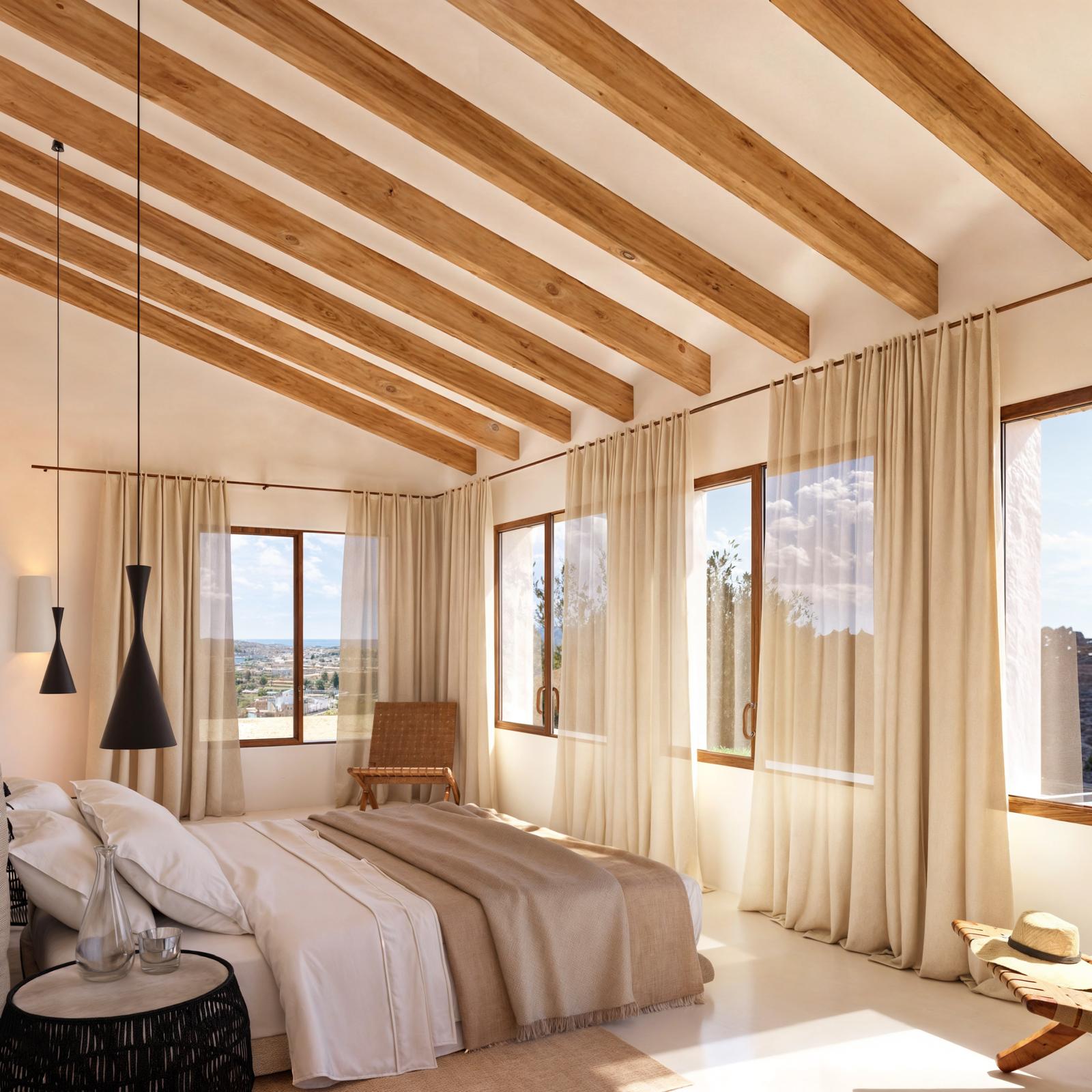 Schlafzimmer mit sichtbaren Deckenbalken aus Holz, großen Holzfenstern und natürlichem Licht mit Panoramablick auf das Meer.