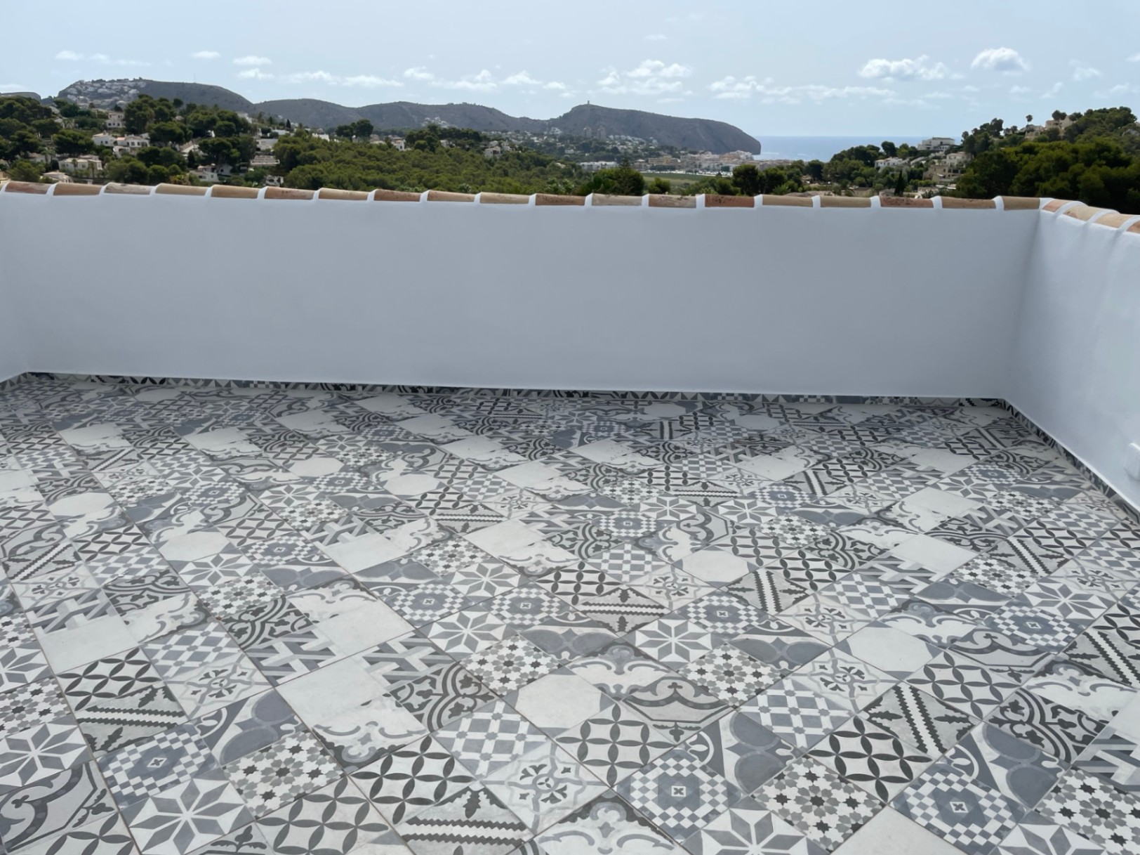 Sonnige Dachterrasse mit dekorativen Musterfliesen und Panoramablick auf das Mittelmeer und die Küste von Moraira.