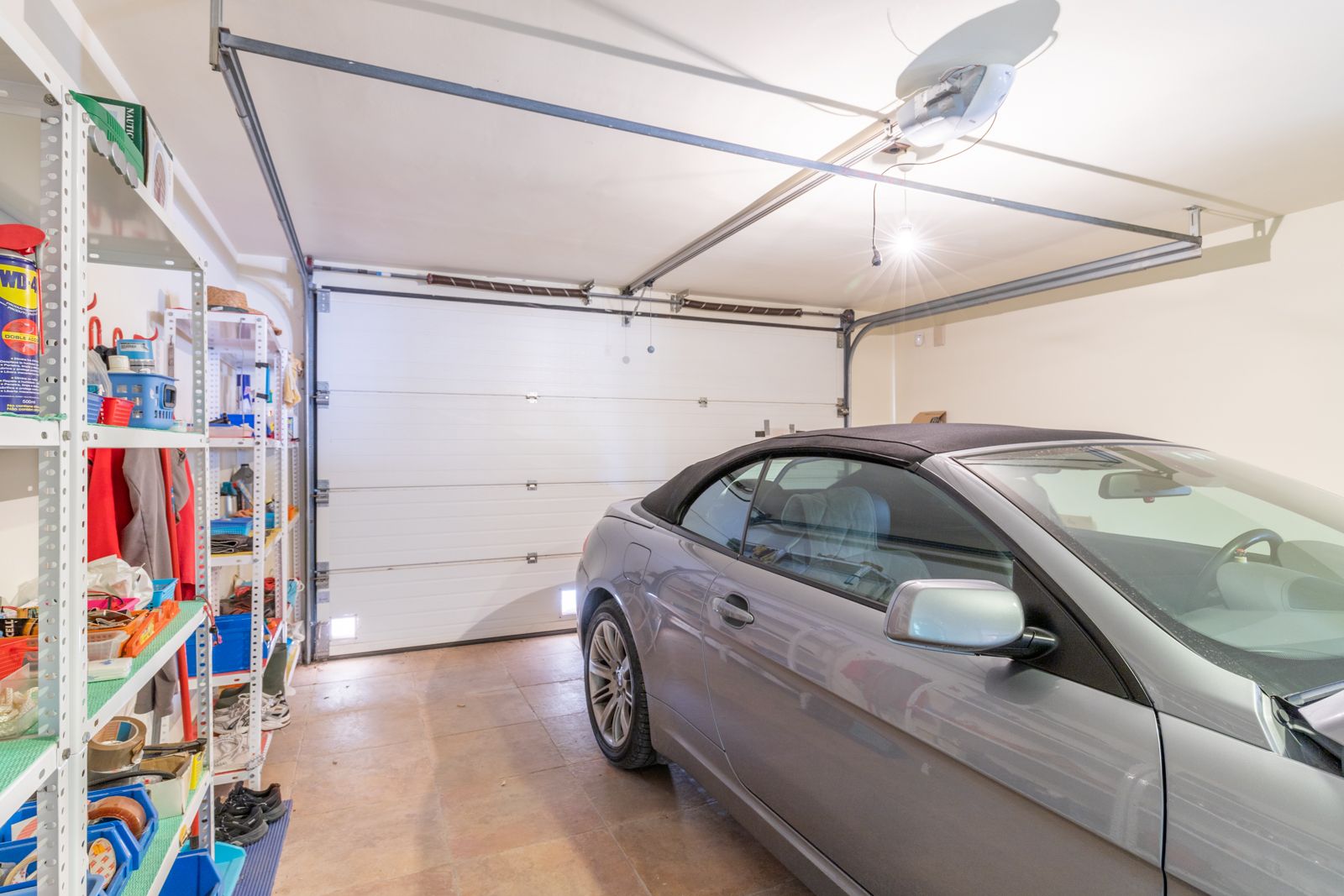Garage mit Metallregalen und grauem Cabrio.