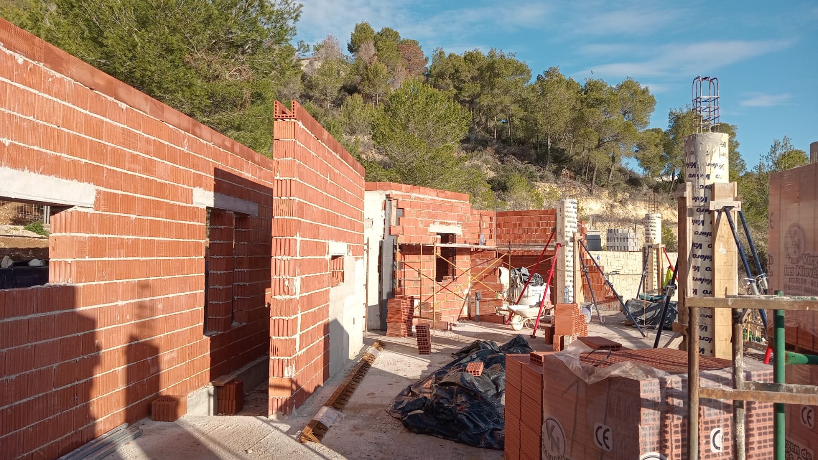 Aktueller Baufortschritt mit Thermo-Tonziegelwänden und Betonsäulen inmitten eines natürlichen Pinienwaldes in Jávea.