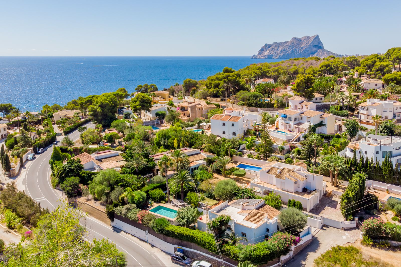 Luftaufnahme der Küste von Baladrar mit Blick auf den Peñón de Ifach. Die Wohngegend zeichnet sich durch ihre Meeresnähe und die üppige mediterrane Vegetation aus.
