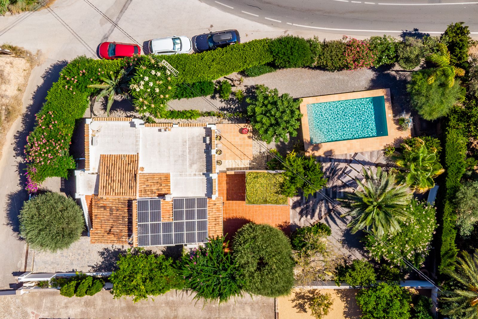 Luftaufnahme des 918 m² großen Grundstücks mit privatem Pool, Solaranlage auf dem Dach und eingewachsenem mediterranem Garten in Draufsicht.