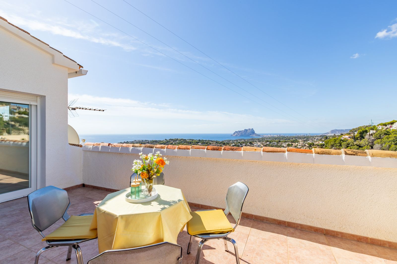Hochgelegene Terrasse mit Keramikfliesen und Panoramablick auf das Mittelmeer und den Peñón de Ifach, inklusive eines sonnigen Sitzbereichs im Freien.