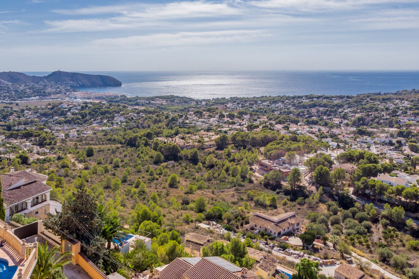 Panoramablick auf das Mittelmeer und das Cap d'Or von Benimeit aus, der die grüne Küstenlandschaft und die Küste von Moraira bei Tageslicht zeigt.
