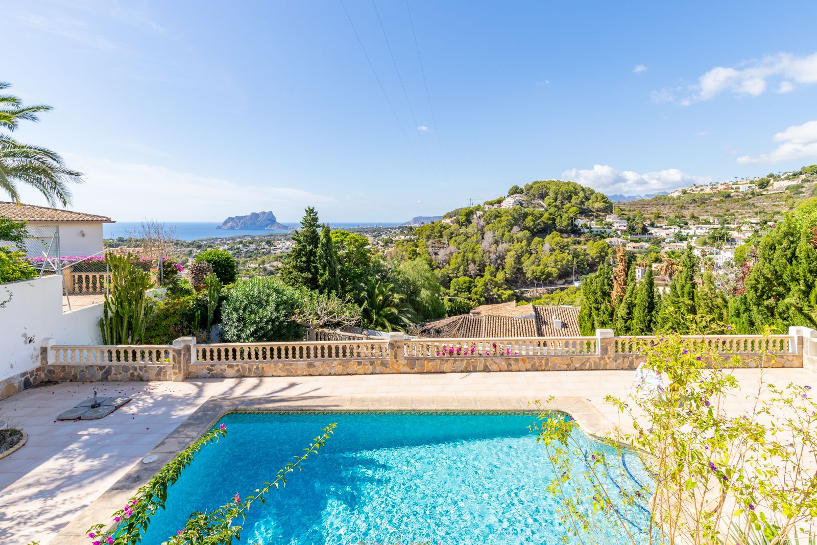 Privater Poolbereich mit Steinterrasse und Balustrade, der einen weitreichenden Panoramablick auf das Mittelmeer und den markanten Peñón de Ifach bietet.