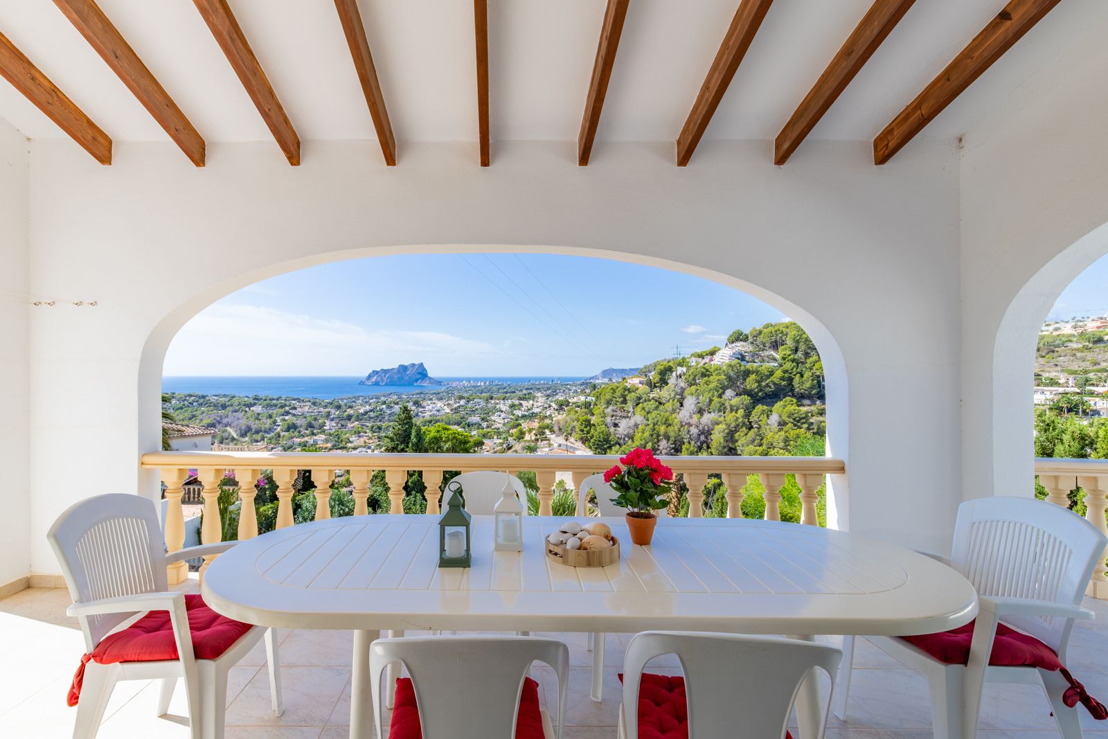 Überdachte Terrasse mit Holzbalken und Rundbögen, die einen Panoramablick auf das Mittelmeer und den Peñón de Ifach über dem Essbereich bietet.