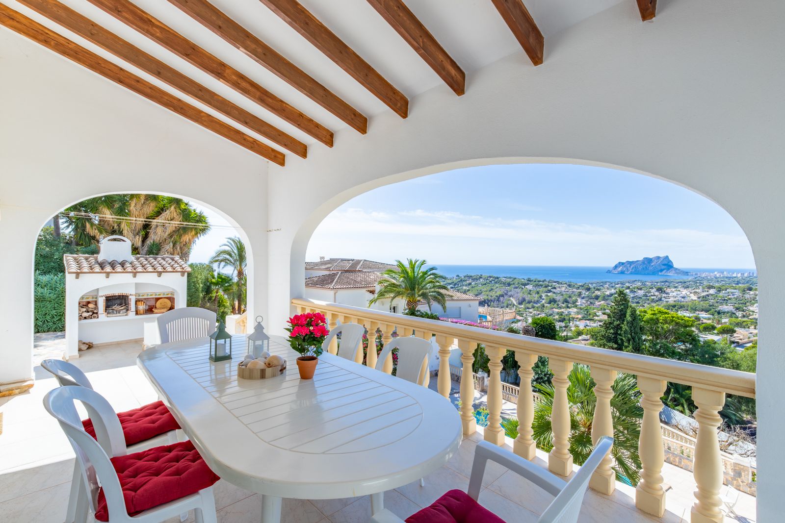 Überdachte Terrasse mit Holzbalkendecke und Essbereich, die einen Panoramablick auf das Meer und den Peñón de Ifach bietet.