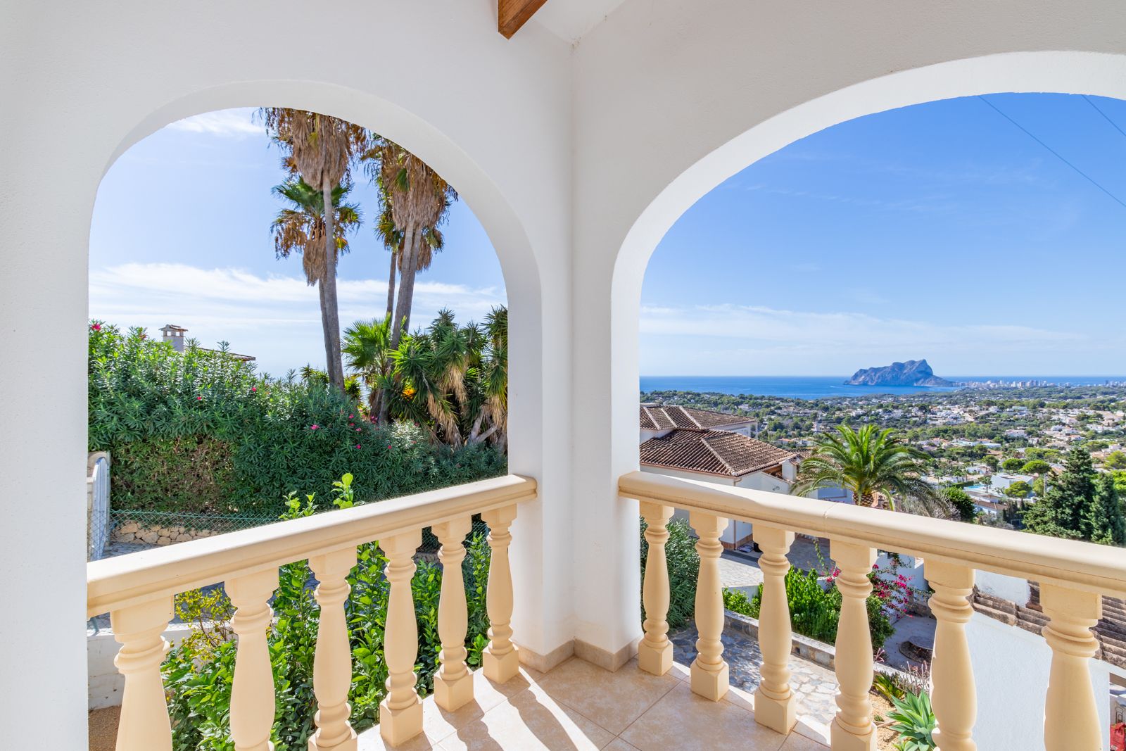 Überdachte Terrasse mit weißen Bögen und klassischer Balustrade, die einen Panoramablick auf das Mittelmeer und den Peñón de Ifach bietet.