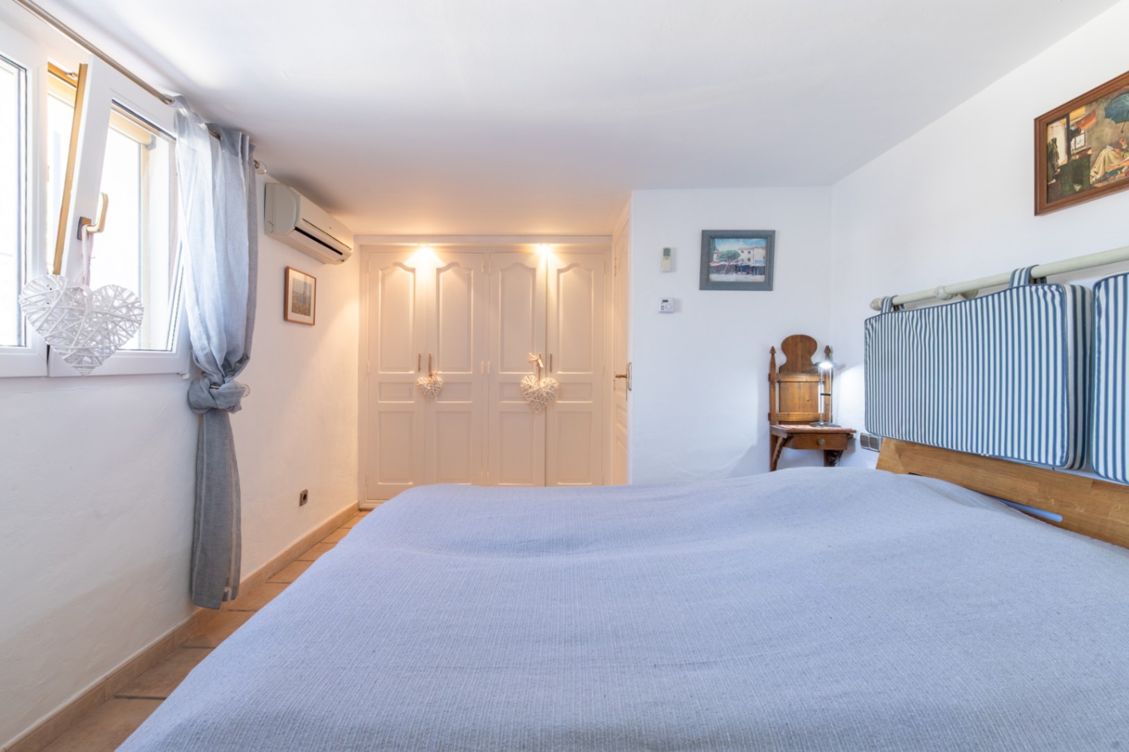 Schlafzimmer mit weißen Einbauschränken, integrierter Beleuchtung, Klimaanlage und doppelt verglasten Fenstern für optimale Energieeffizienz.