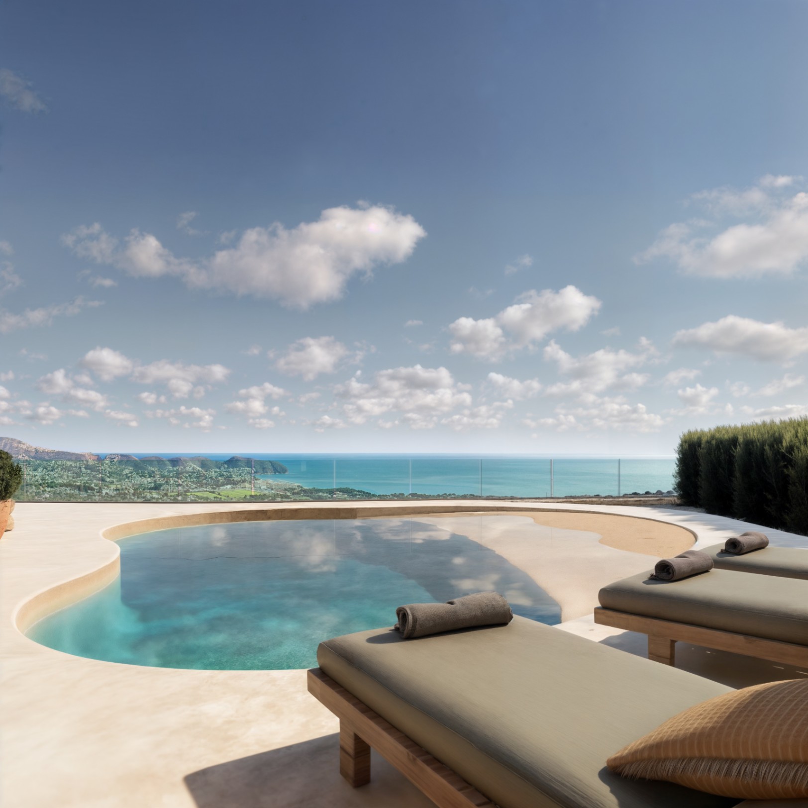Außenterrasse mit organisch geformtem Pool, Strandzugang, Holzsonnenliegen und Panoramablick auf das Mittelmeer durch eine Glasbalustrade.