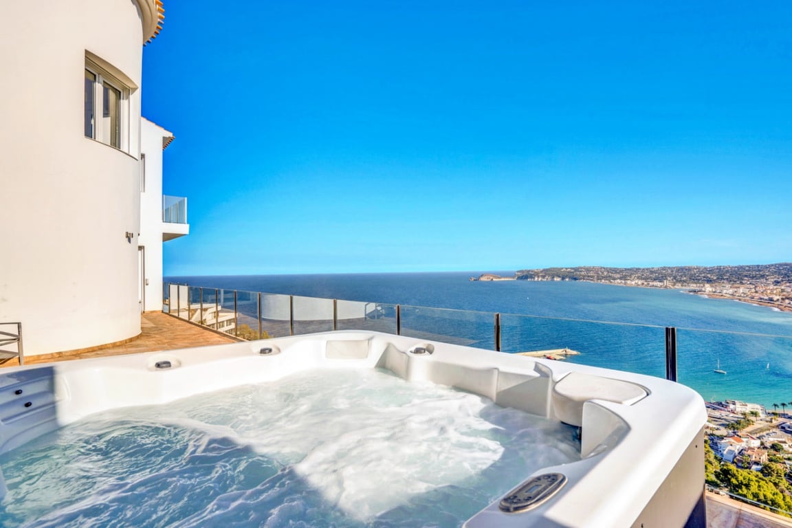 Außen-Whirlpool auf einer Terrasse mit Glasgeländer und Panoramablick auf das Mittelmeer und die Bucht von Jávea.