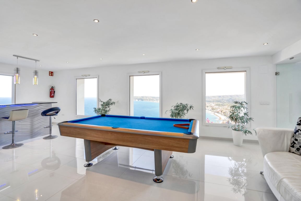 Spielzimmer mit Billardtisch, integriertem Barbereich und großen Fenstern mit Panoramablick auf das Mittelmeer und die Küste von Jávea.