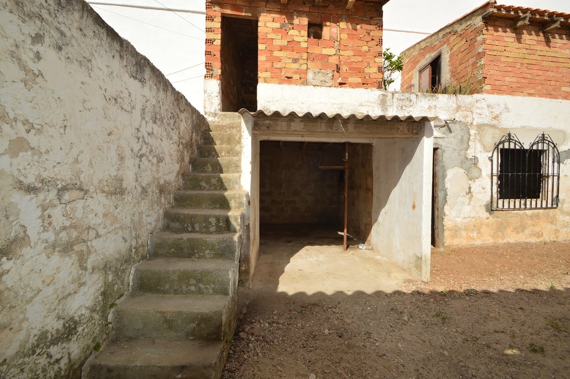 Außenhof mit Betontreppe, überdachtem Lagerbereich und freiliegenden Backsteinmauern, ideal für ein Renovierungsprojekt in der Altstadt.