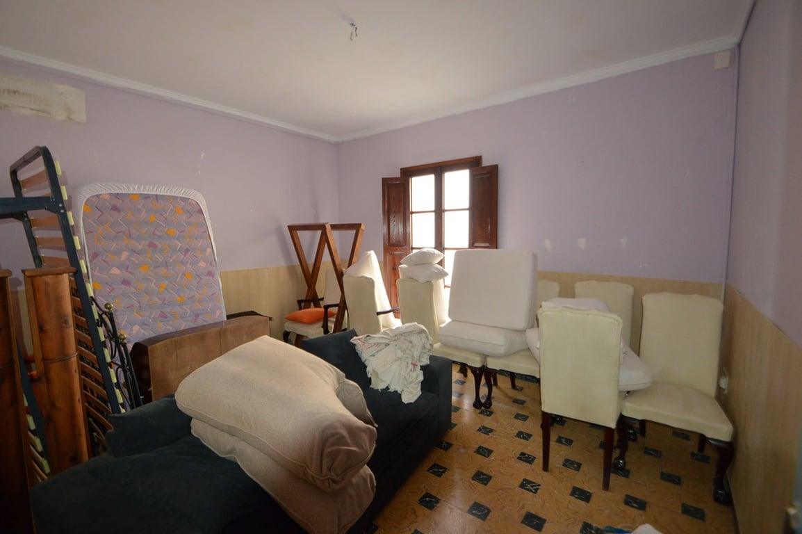 Geräumiges Zimmer mit lavendelfarbenen Wänden, Holzpaneelen, traditionellem Fliesenboden und einem klassischen Holzfenster mit Innenläden.