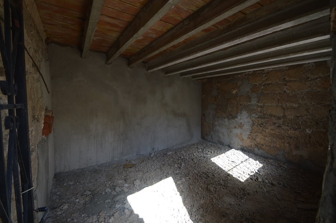 Unausgebauter Lagerraum mit originalen Steinwänden, sichtbaren Deckenbalken und natürlichem Lichteinfall, ideal für den Ausbau zum Hobbyraum.