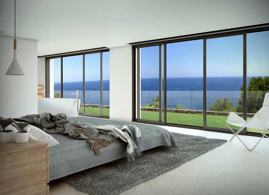 Minimalistisches Schlafzimmer mit bodentiefen Glasschiebetüren, grauen Textilien und Panoramablick auf das Mittelmeer über eine gepflegte Rasenfläche.