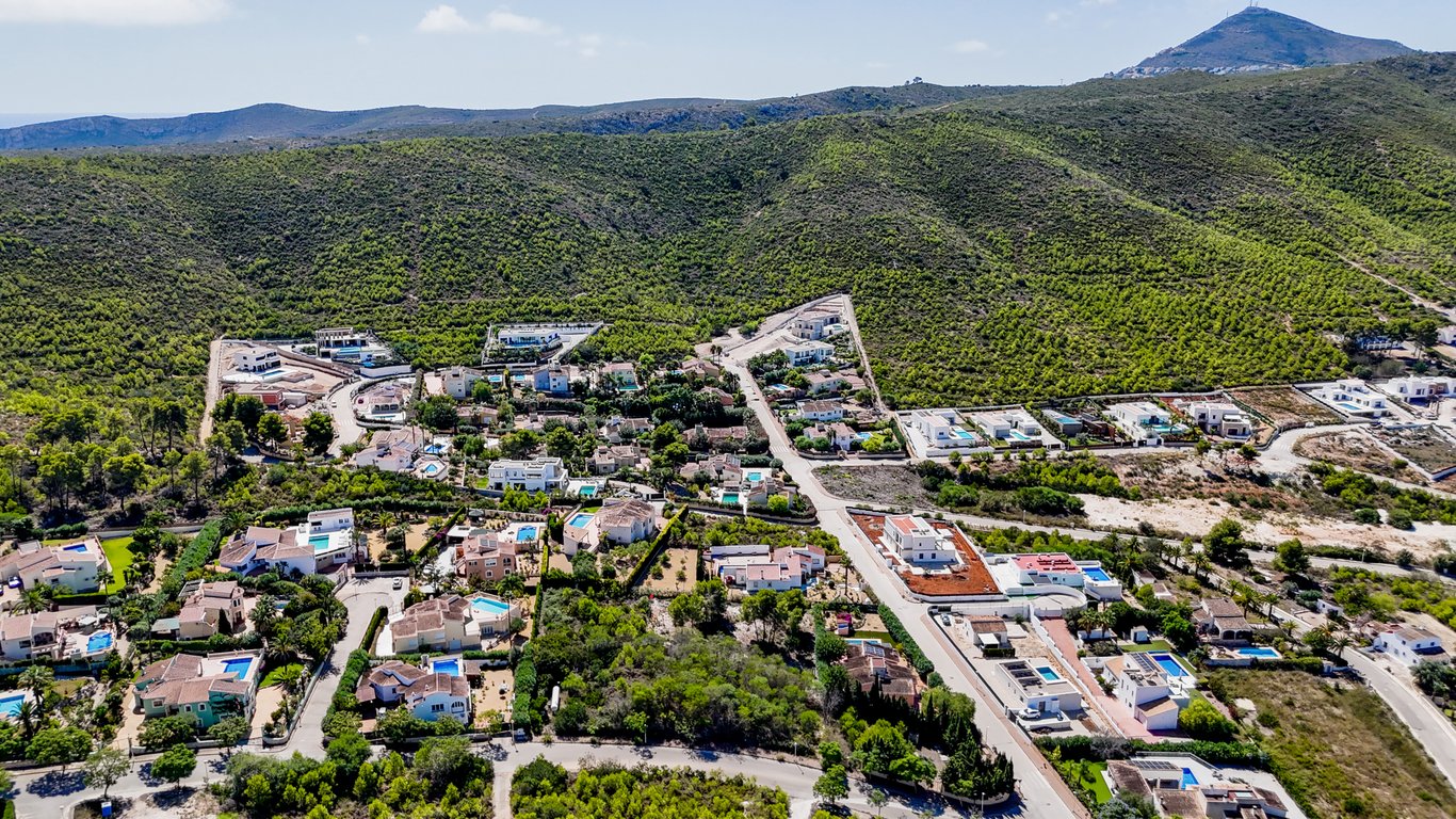Luftaufnahme des Wohngebiets in Jávea, die die ruhige Lage der Villa inmitten grüner Hügel und mediterraner Landschaft zeigt.