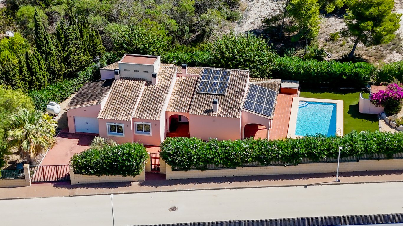 Luftbild der eingeschossigen Villa mit privatem Pool, Photovoltaikanlage auf dem Ziegeldach und einem umzäunten Grundstück mit Garage in ruhiger Lage.