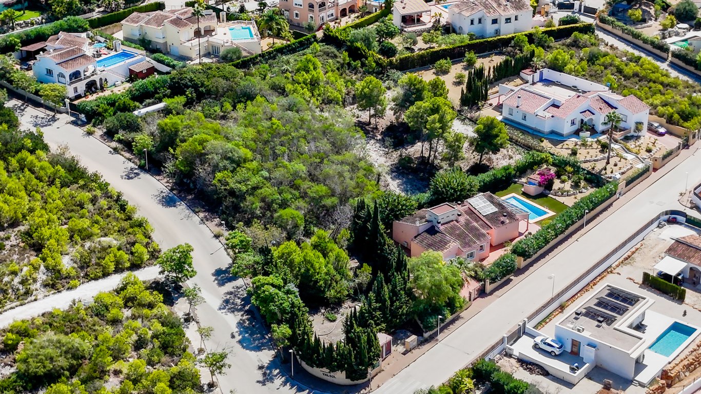 Luftbild der Villa mit ebenerdigem Grundriss, privatem Pool und Solaranlage auf einem komplett eingezäunten, flachen Grundstück im Grünen.