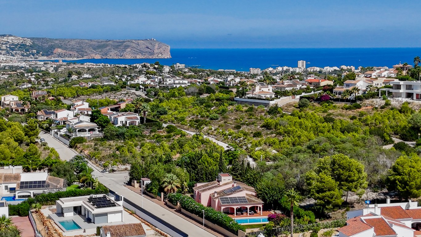 Erhöhte Panoramaaufnahme der Villa mit Photovoltaikanlage und Pool, eingebettet in die mediterrane Landschaft mit weitem Blick auf das Meer und die Küste.