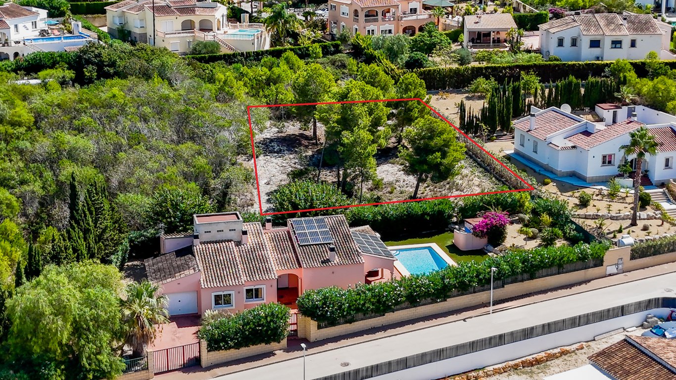 Luftaufnahme der Villa mit Solaranlage und Pool, die das angrenzende, rot markierte Baugrundstück in Jávea zeigt.