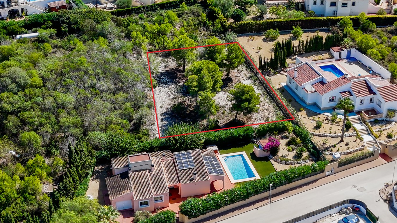 Luftaufnahme der Villa mit Sonnenkollektoren und Pool sowie des angrenzenden, rot markierten Baugrundstücks mit altem Baumbestand.